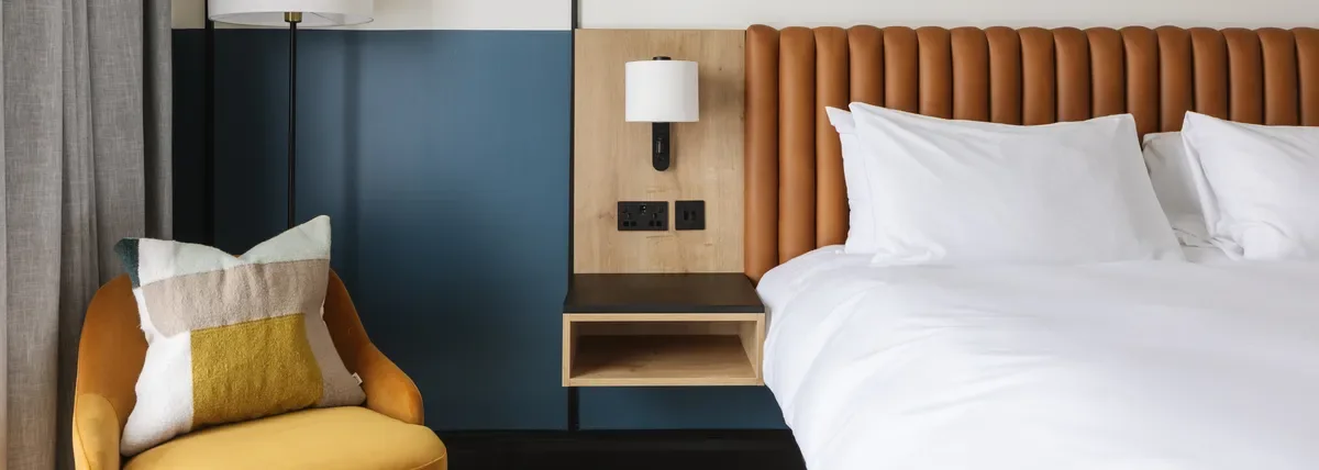 Full-wall hotel headboard design with integrated lighting and bedside area