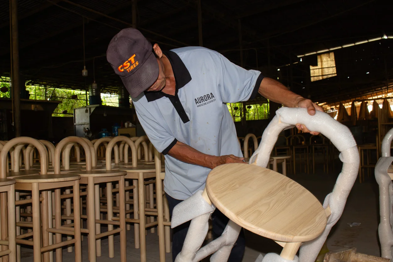 Chair protection wrapping before export packing Worker wrapping a furniture chair with protective foam before packing