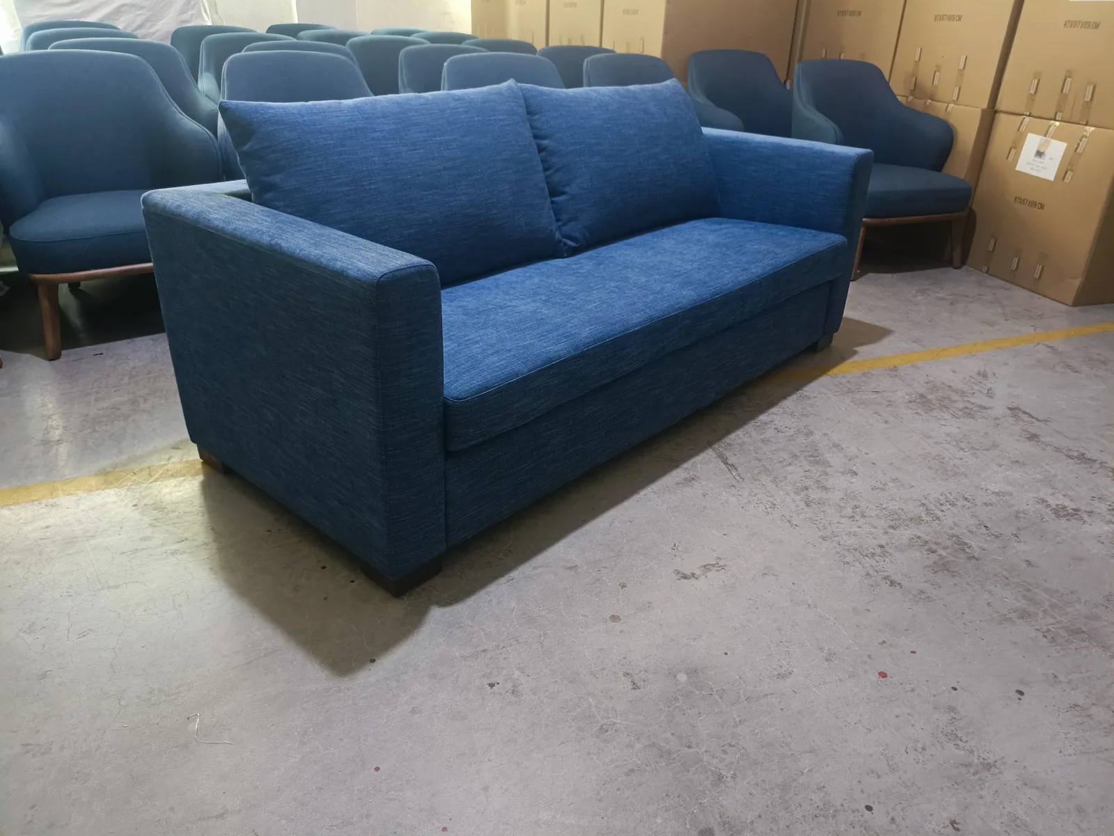 Blue upholstered sofa shown at an angle in the workshop