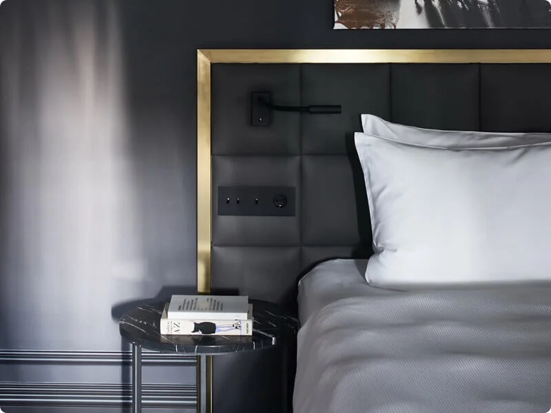 Upholstered hotel headboard with bedside socket and wall light detail