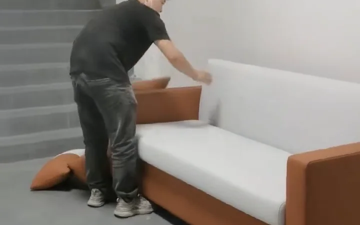 Worker removing loose cushions before partially disassembling a sofa for moving