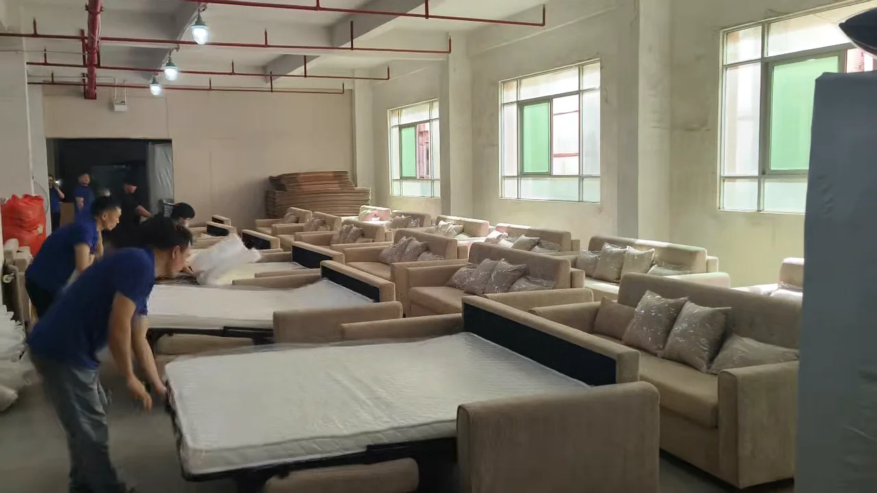 Workers checking several pull-out sofa beds opened on a factory floor