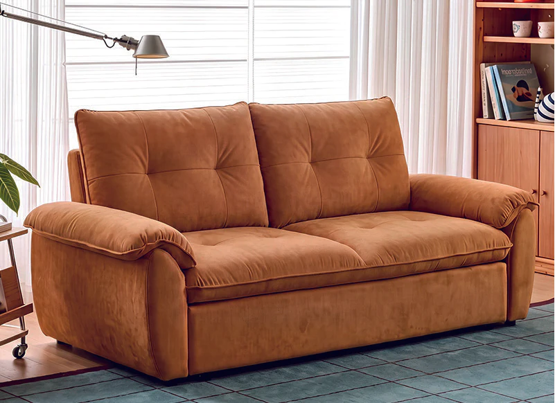 Warm tan manual pull-out sofa bed with rounded padded arms and two back cushions