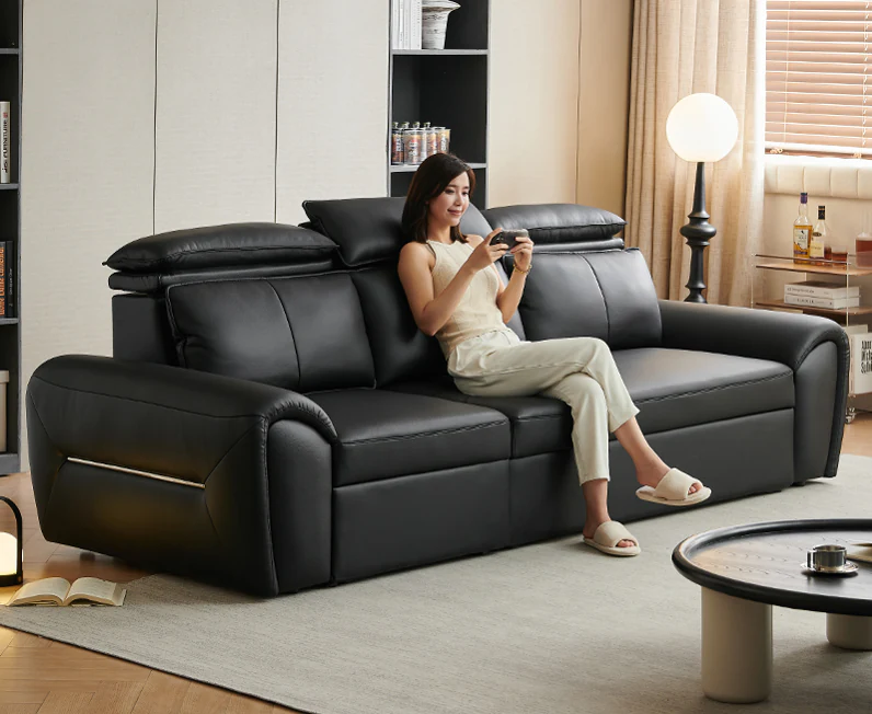 Black pull-out sofa bed with raised headrests and metal-trimmed padded arms
