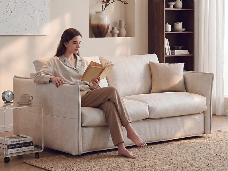 Light-sage slim-arm fold-out sofa bed with loose cushions in sofa mode