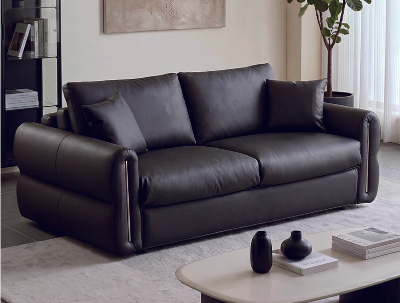 Black rolled-arm fold-out sleeper sofa with piped leather-look cushions