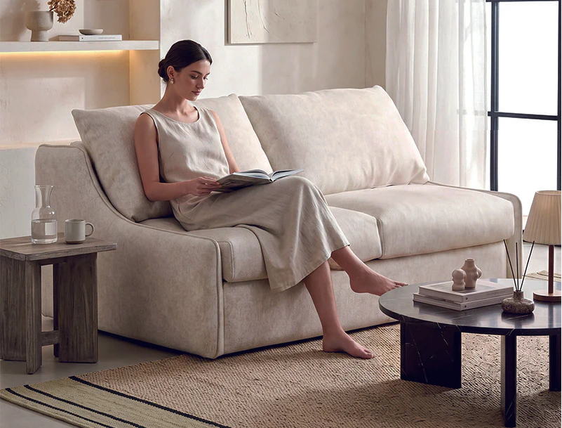 Ivory fold-out sofa bed with soft flared arms and tall loose cushions
