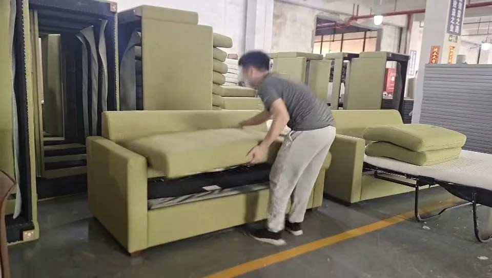 Worker lifting the seat section of a green manual pull-out sofa bed