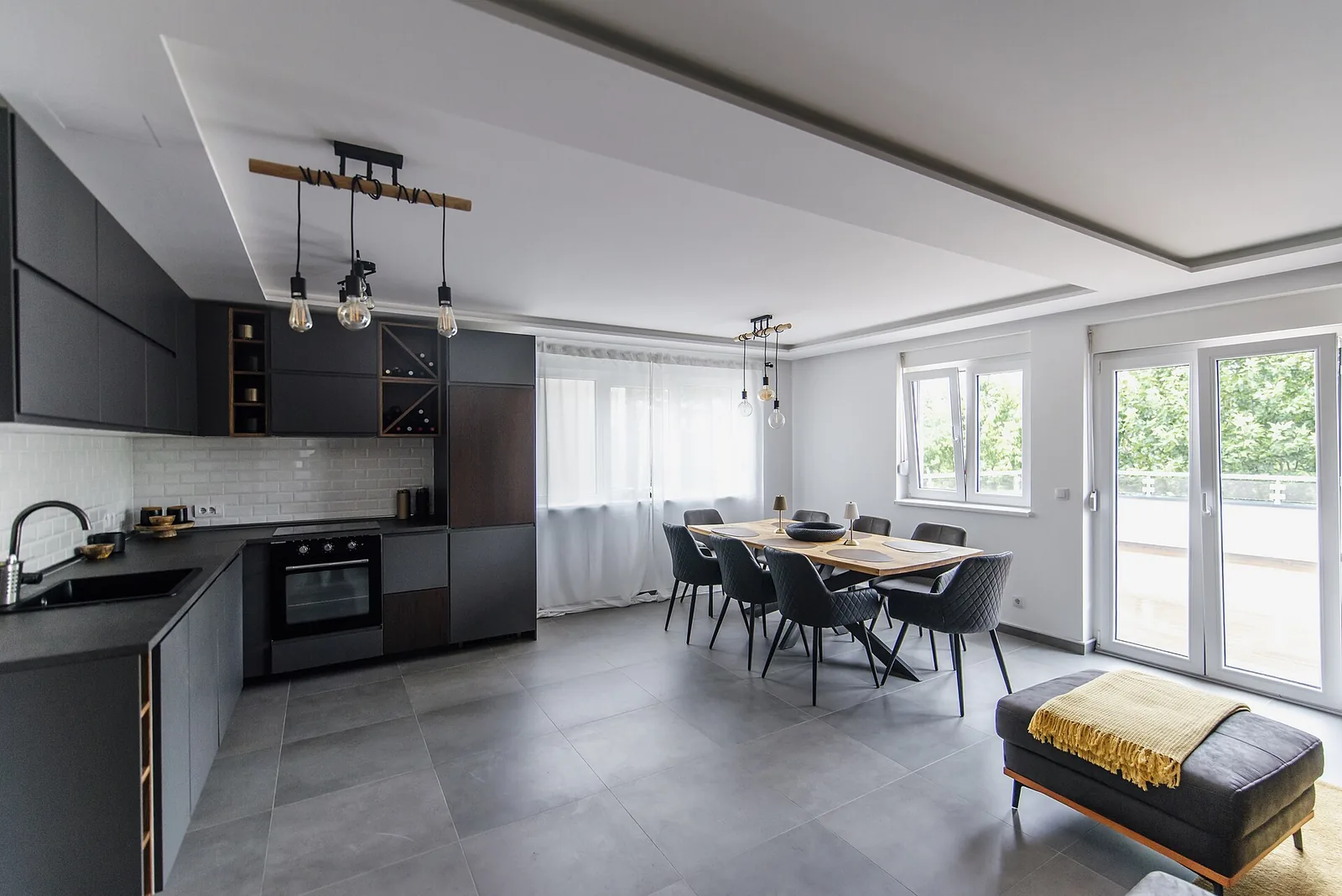 Dark dining chairs around a table in a bright open dining room