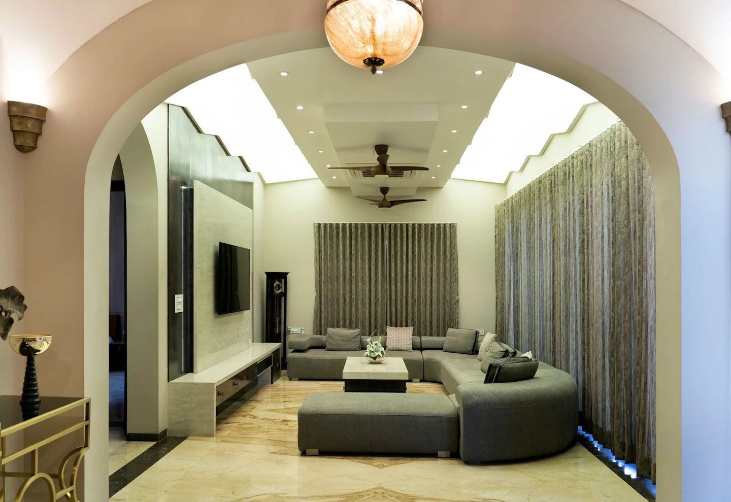 Grey rounded sectional seating and an ottoman in a room with arched openings