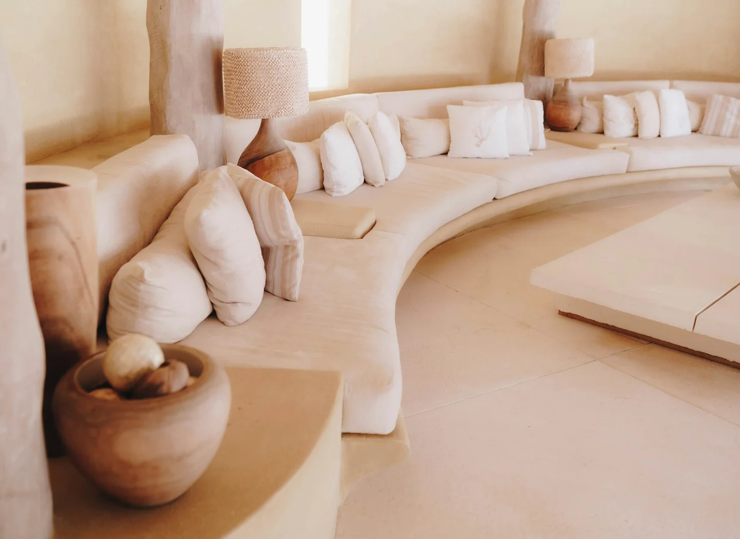 A long pale curved sofa beside a low table in a coordinated lounge