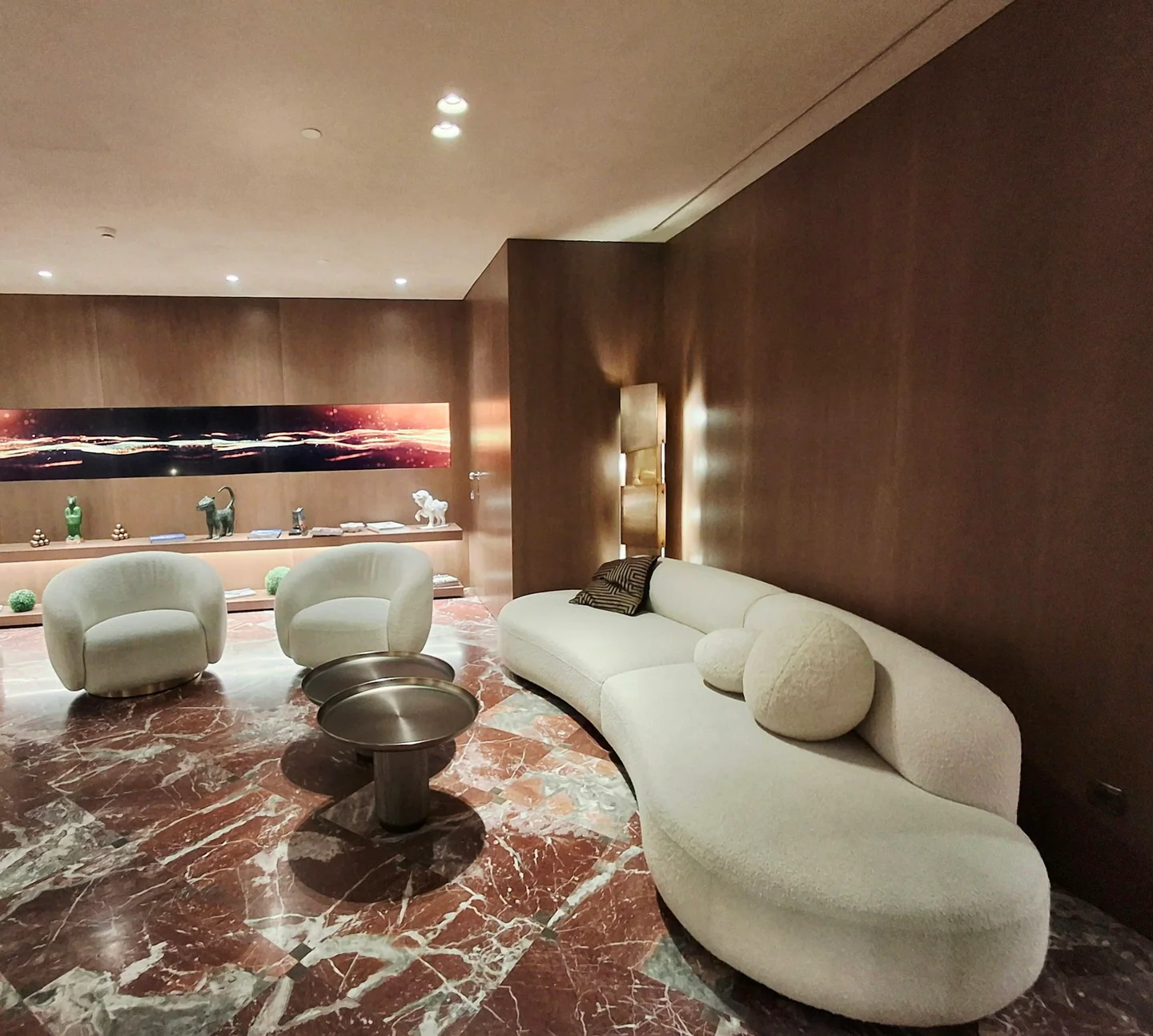 A pale curved sofa and lounge chairs on a polished stone floor