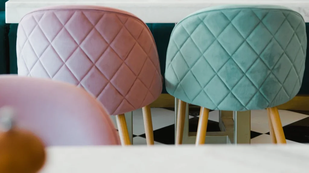 Pastel upholstered cafe chairs with gold-tone legs at a white table