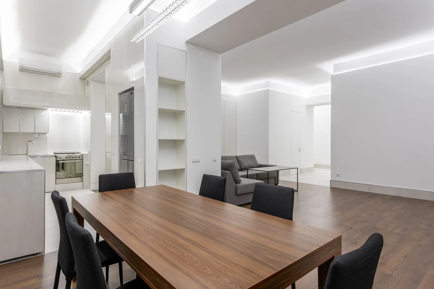 Dark upholstered dining chairs around a wooden table in a light apartment