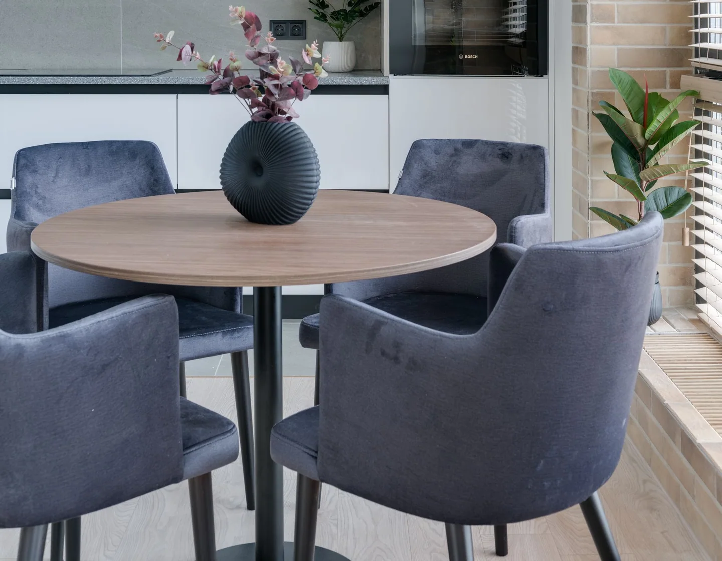 Blue upholstered dining armchairs around a round table in a bright apartment
