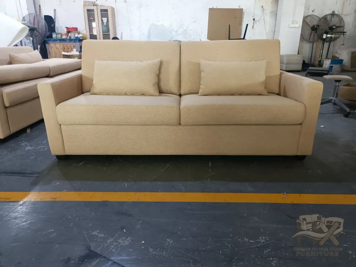 Beige upholstered pull-out sofa bed in closed mode at the workshop