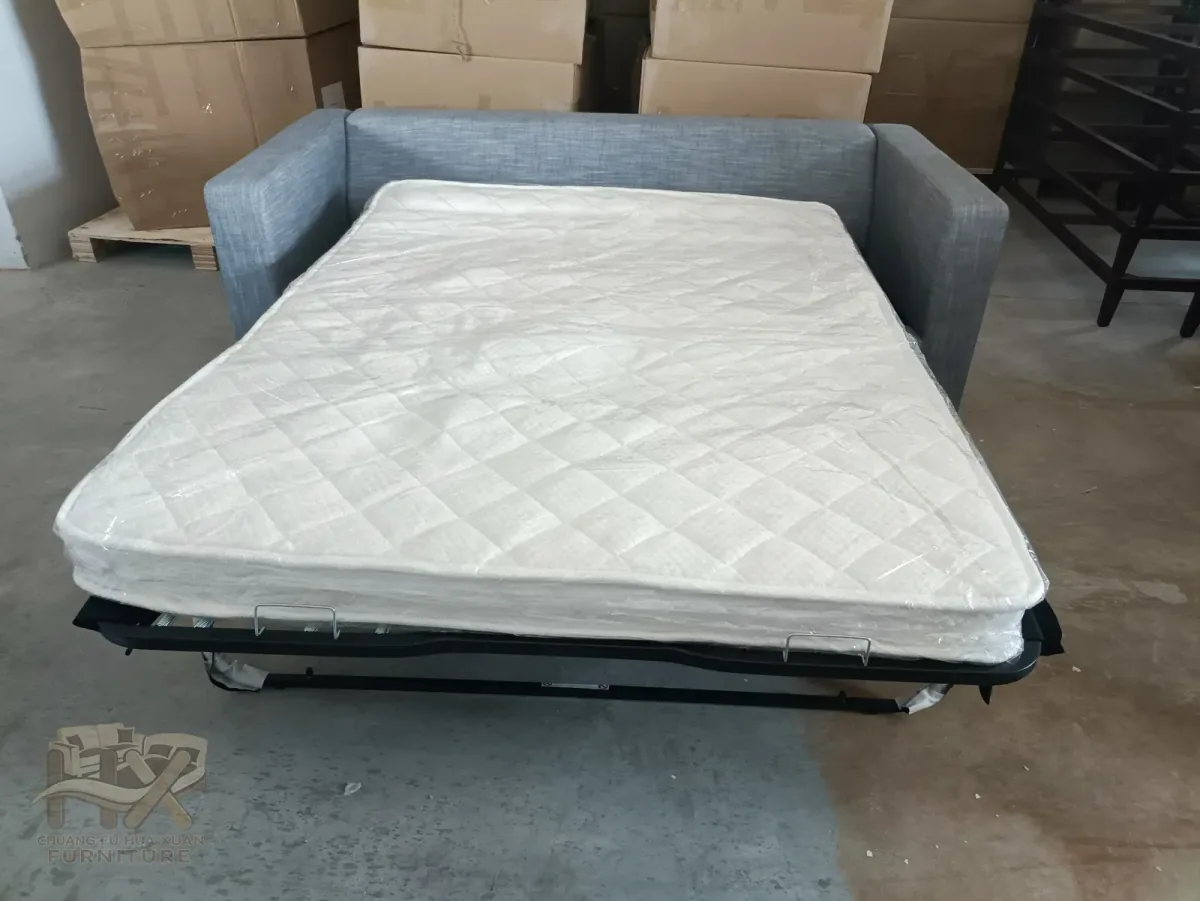 Grey fabric sleeper sofa opened with separate mattress and metal base visible